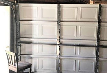 Warped and dented garage door awaiting replacement in La Mesa
