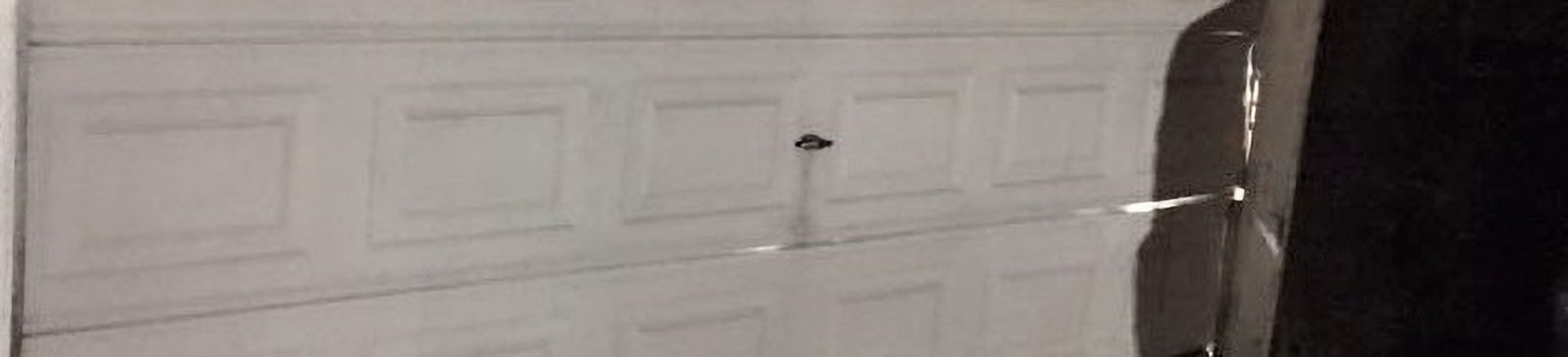 Warped and dented garage door awaiting replacement in La Mesa