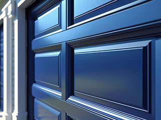 Glossy blue paneled garage door on a residential home, reflecting quality installation and maintenance by local La Mesa specialists.